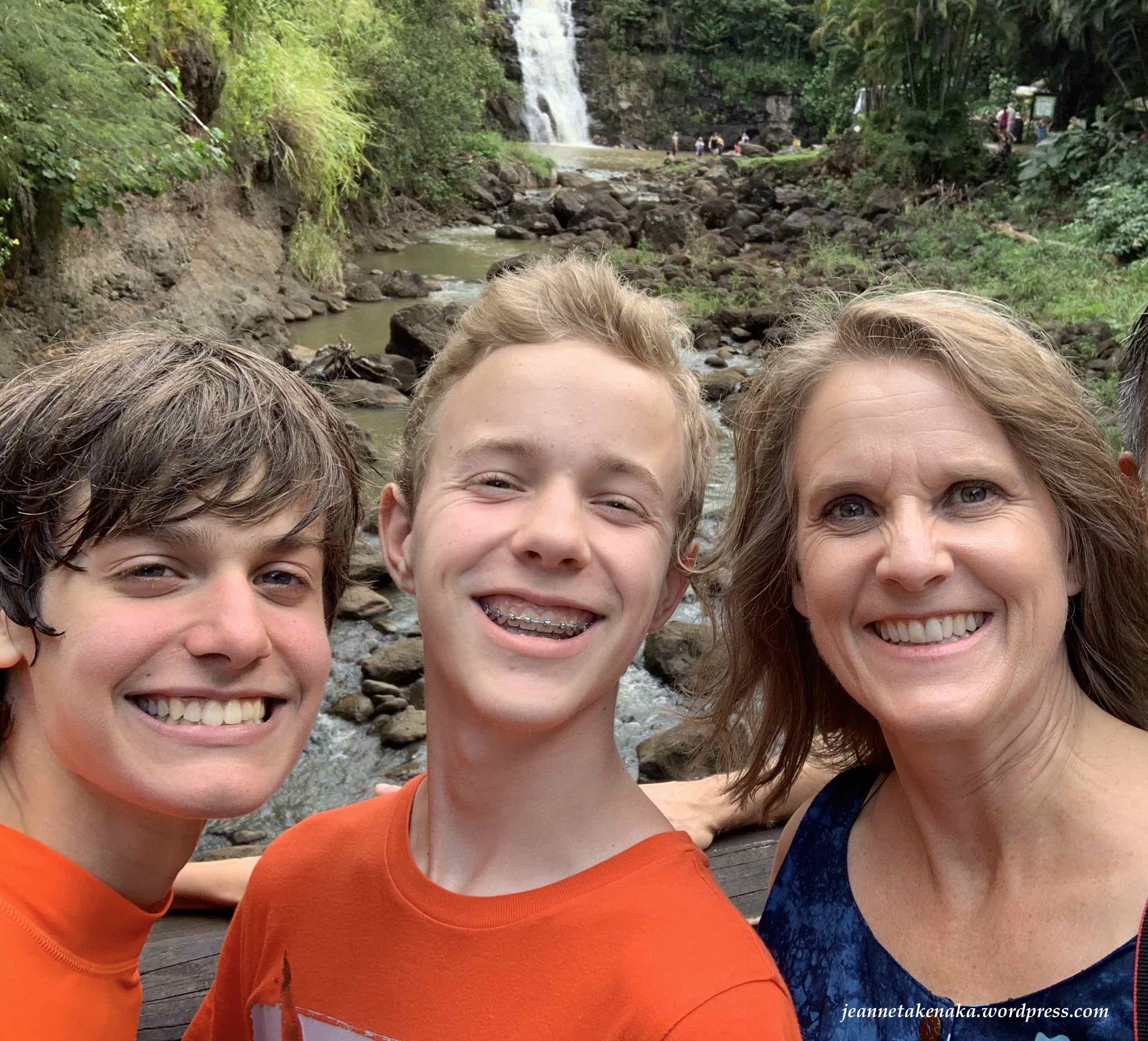A woman standing with her two sons in front of a water fall