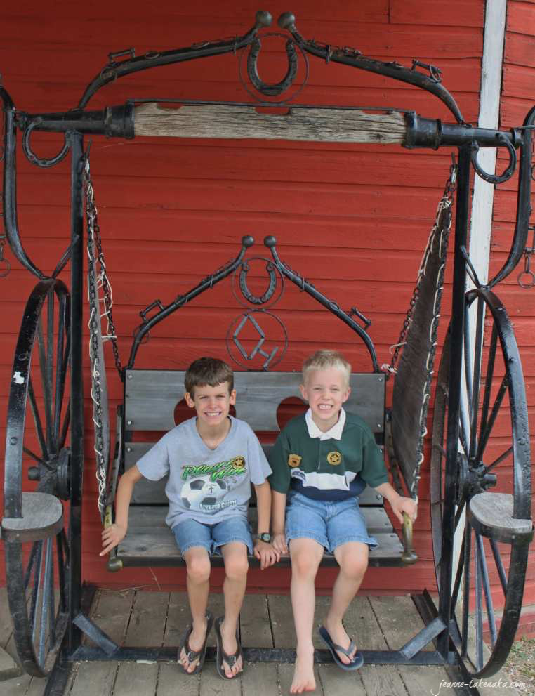 Two boys sitting on a swing together